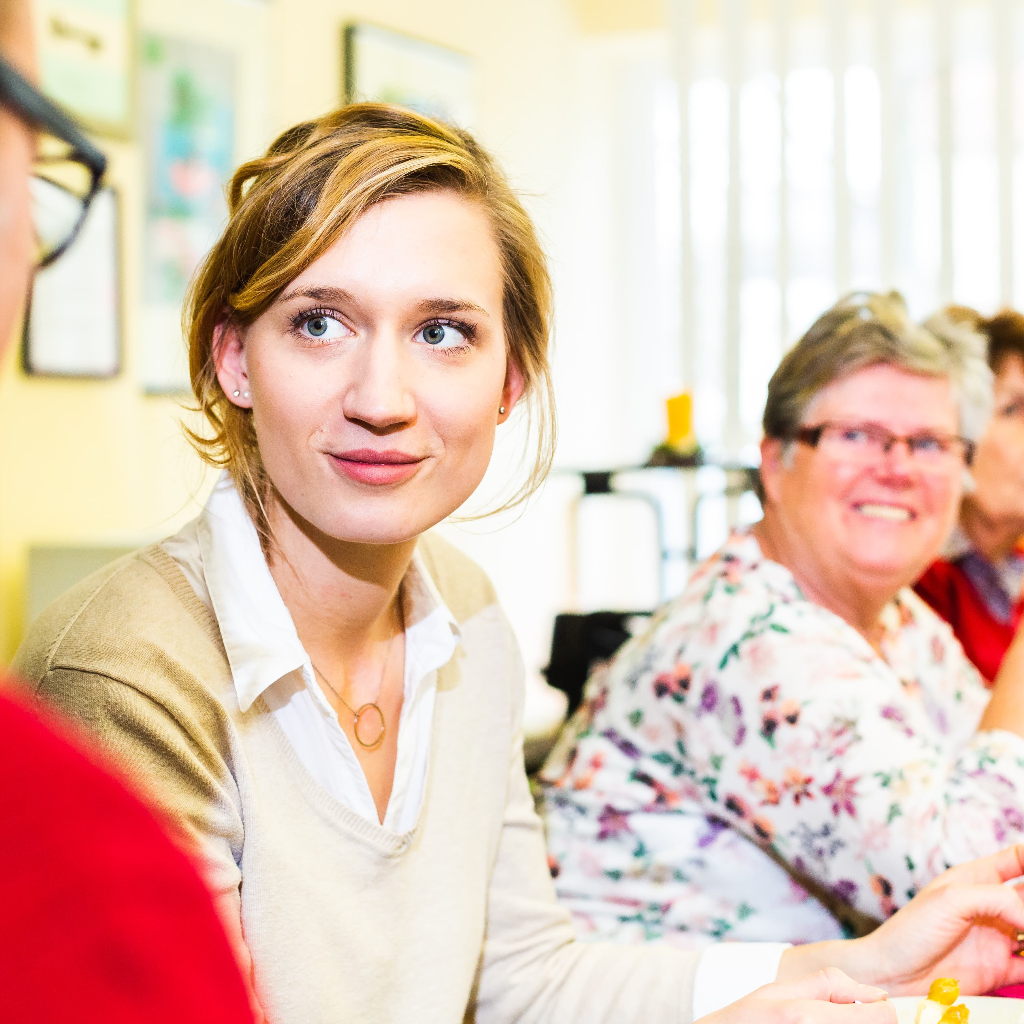 Gedeckter Tisch im Mietertreff mit Menschen, die sich angeregt unterhalten 